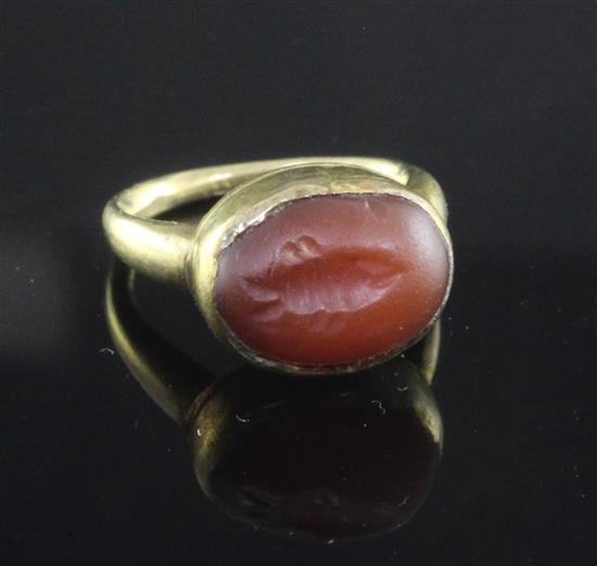 A small yellow metal ring, possibly Roman, set cabochon carnelian carved with a fish,